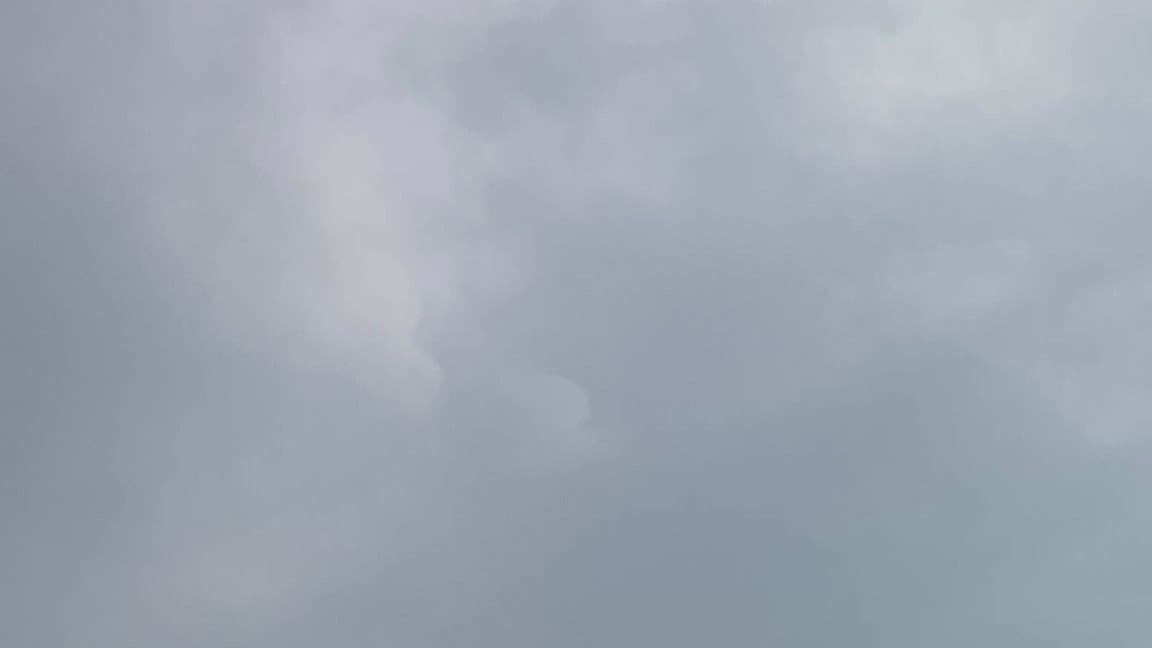 A patch of sky full of gray clouds, with the faint contours of some whiter clouds about one-third of the way across the frame catching light from the right.