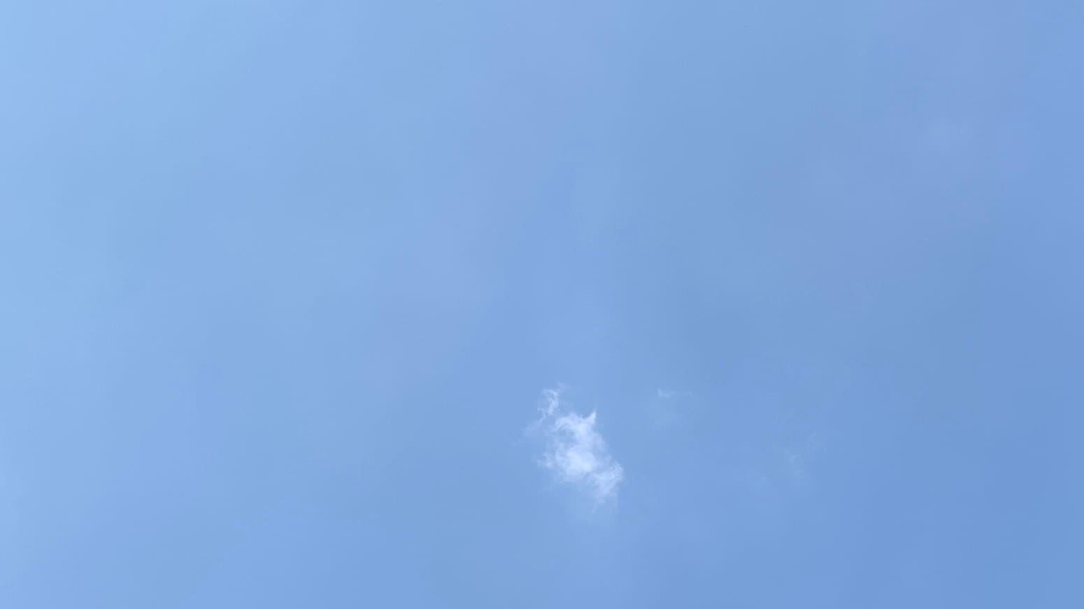 A patch of hazy light-blue sky with a sort of ovoid shred of fractus cloud in the lower center of the frame. 