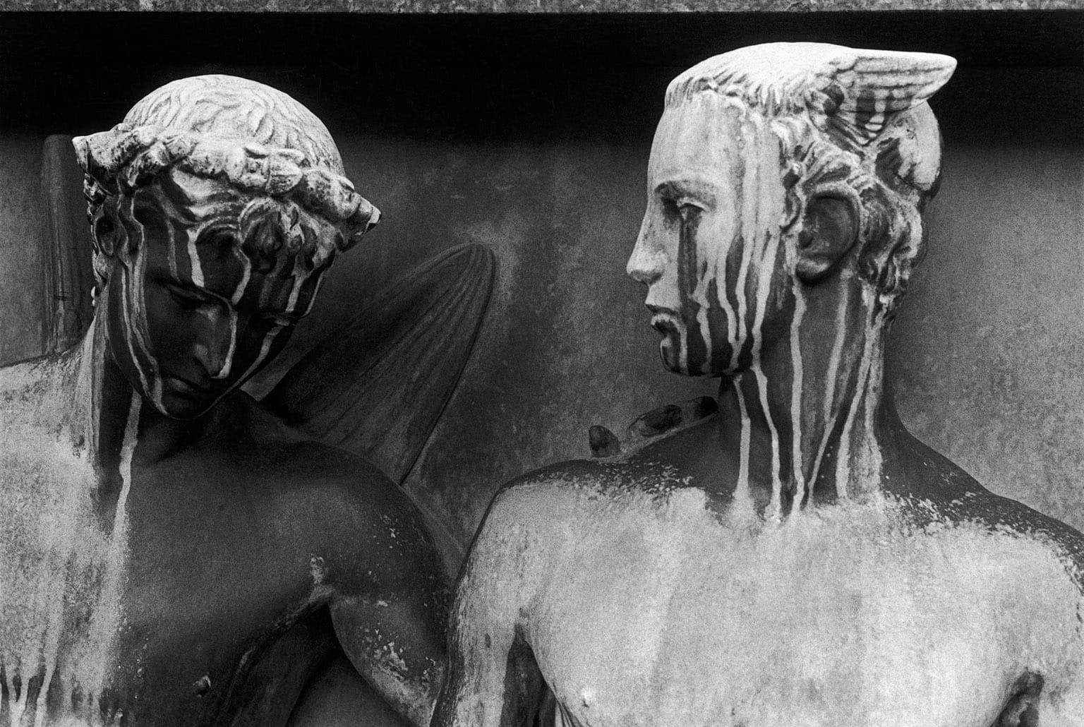 Two figures with discoloration streaming down from the tops of their heads so it looks like they're sweating real bad
