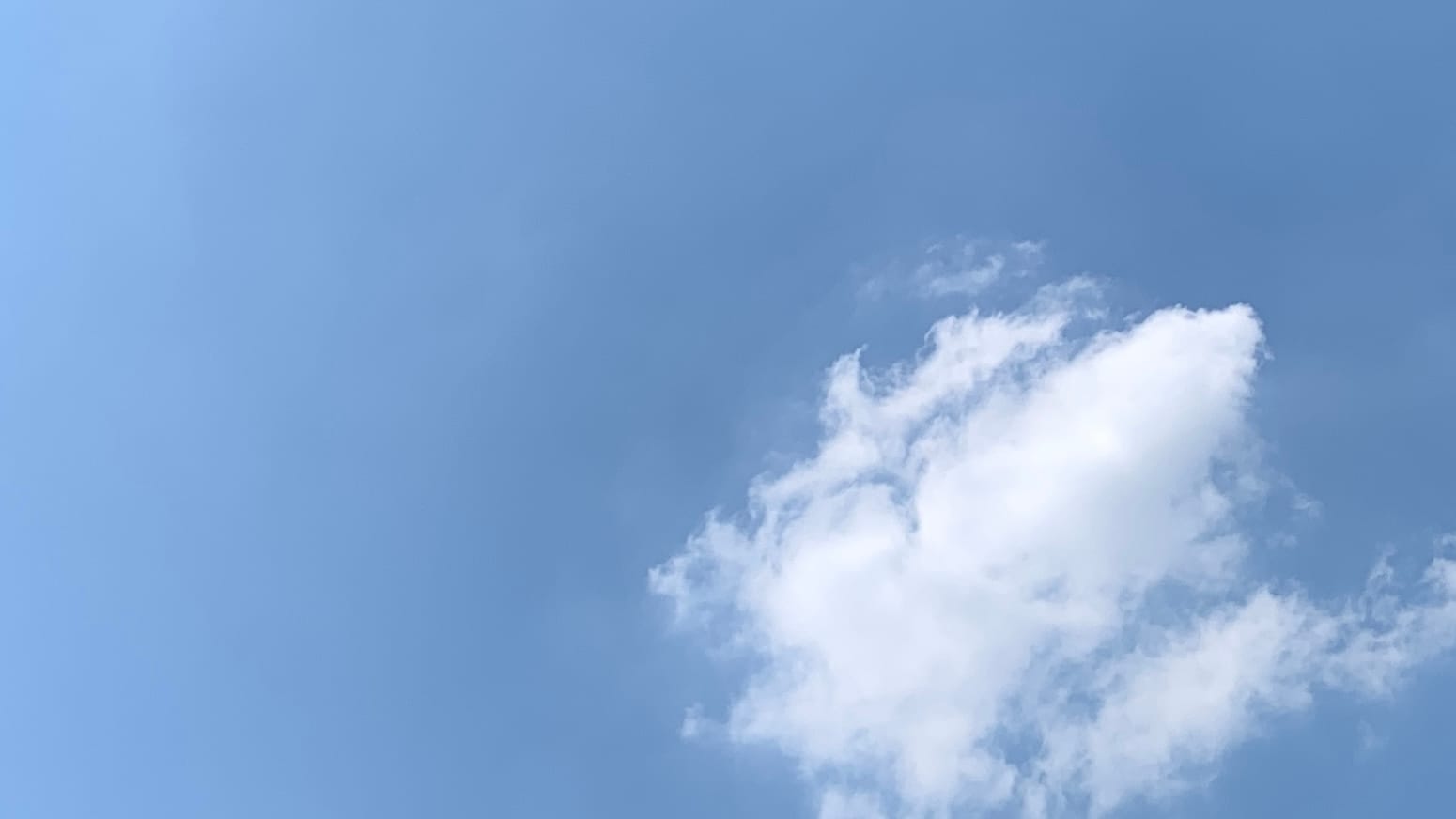 Slightly faded blue sky with a big dab of cumulus, cut with gaps of blue, in the lower right-hand part of the frame.