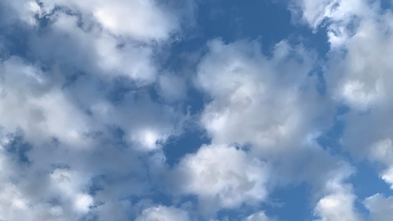 A sky of broken white and gray clouds over deep blue. 
