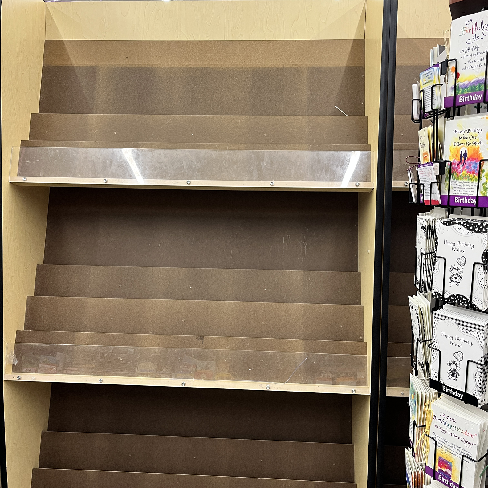 Empty rack at the supermarket next to the greeting cards