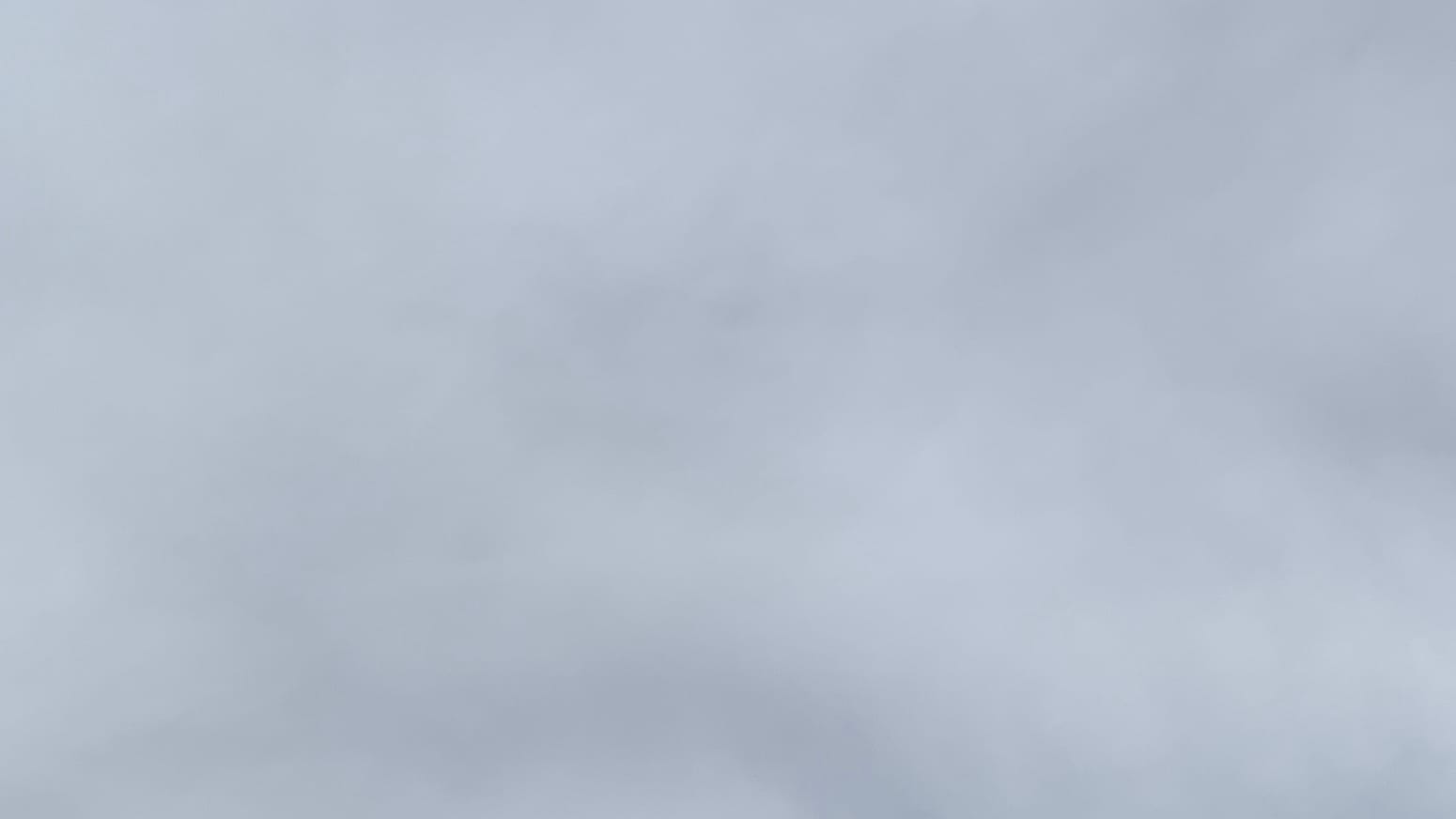 A patch of gray sky with vague slightly darker gray shapes in it.