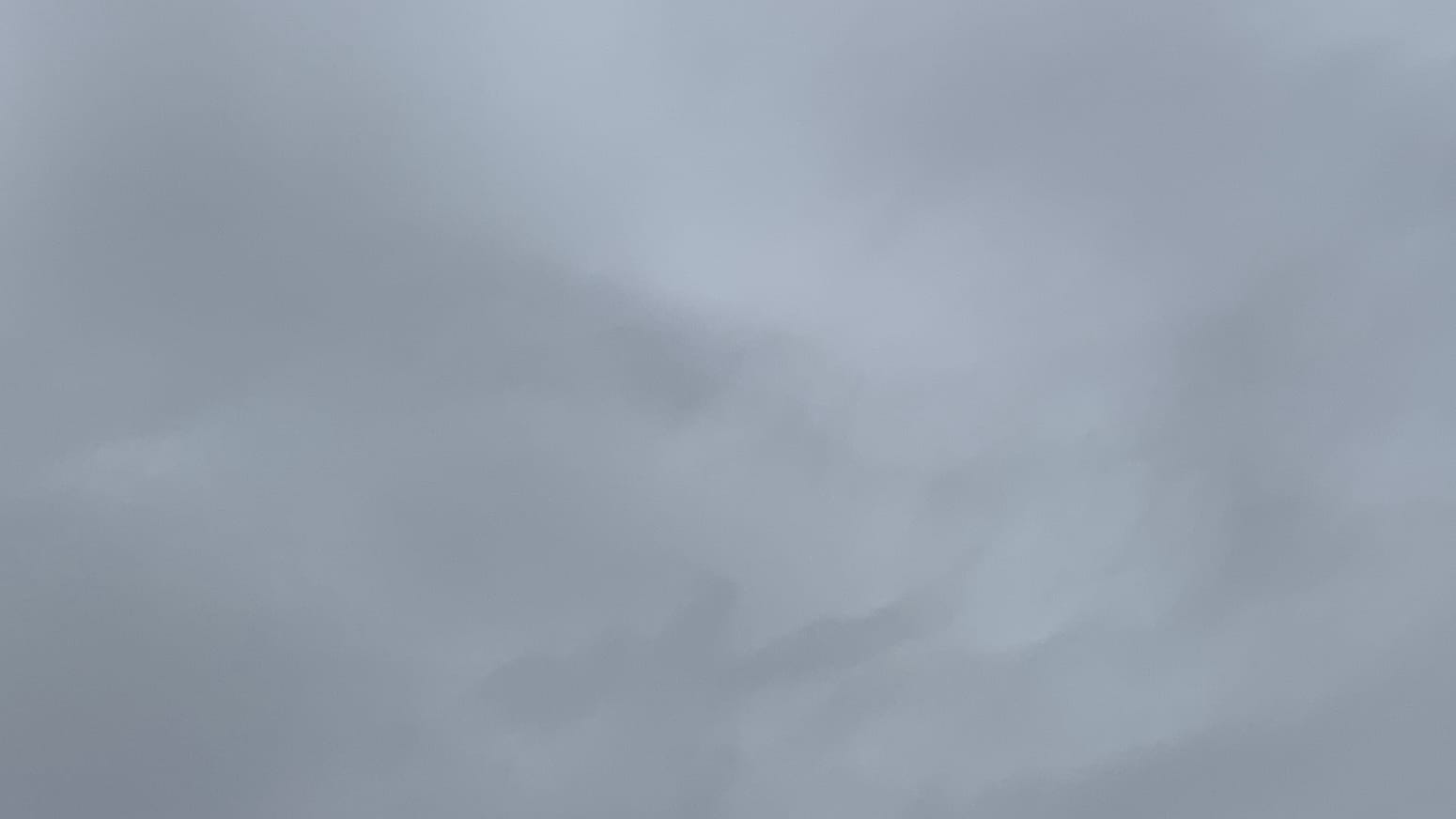 A patch of gray cloudy sky with slightly darker swirls of gray coming in from the left and extending faintly across the middle