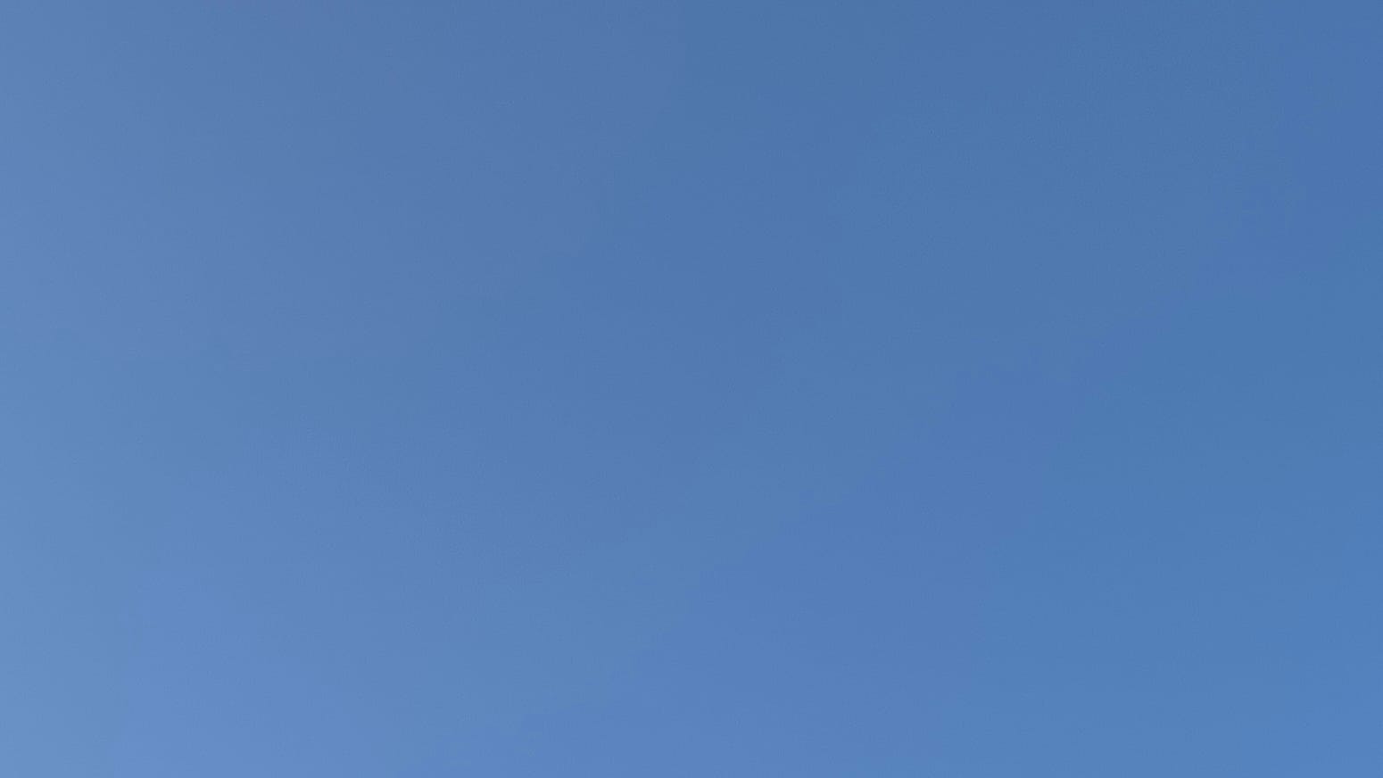 A patch of clear sky in a slightly faded or smoky blue. 