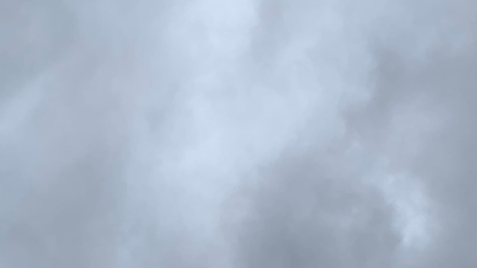 A patch of uneven gray sky, lighter in the middle and darkest toward the lower right corner. 