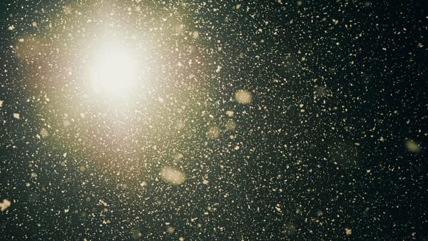 Snowflakes falling seen from below against a bright light at night